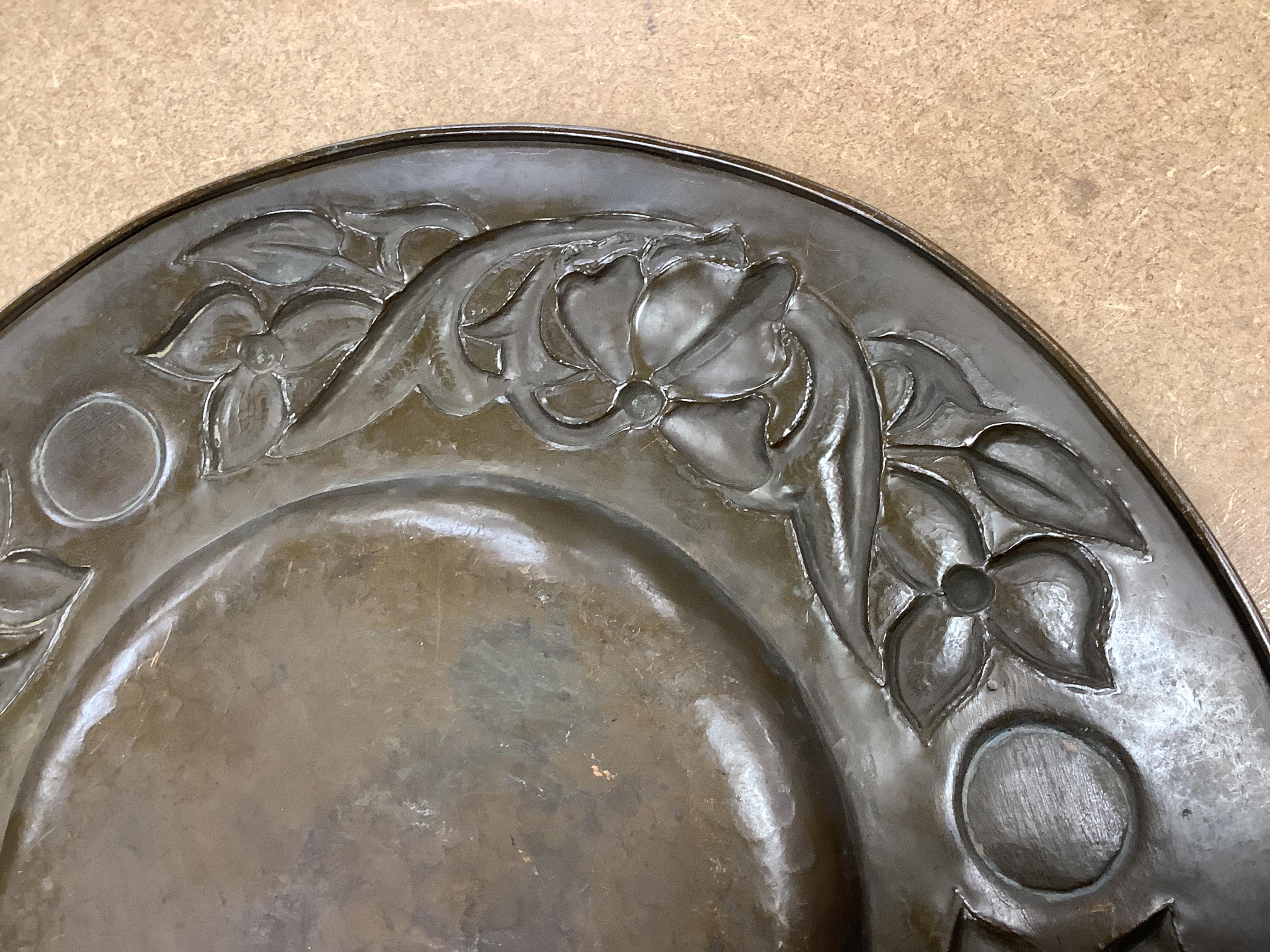 An Arts and Crafts embossed copper dish, in the manner of John Pearson, inlaid with Ruskin cabochons, unsigned, 32cm in diameter